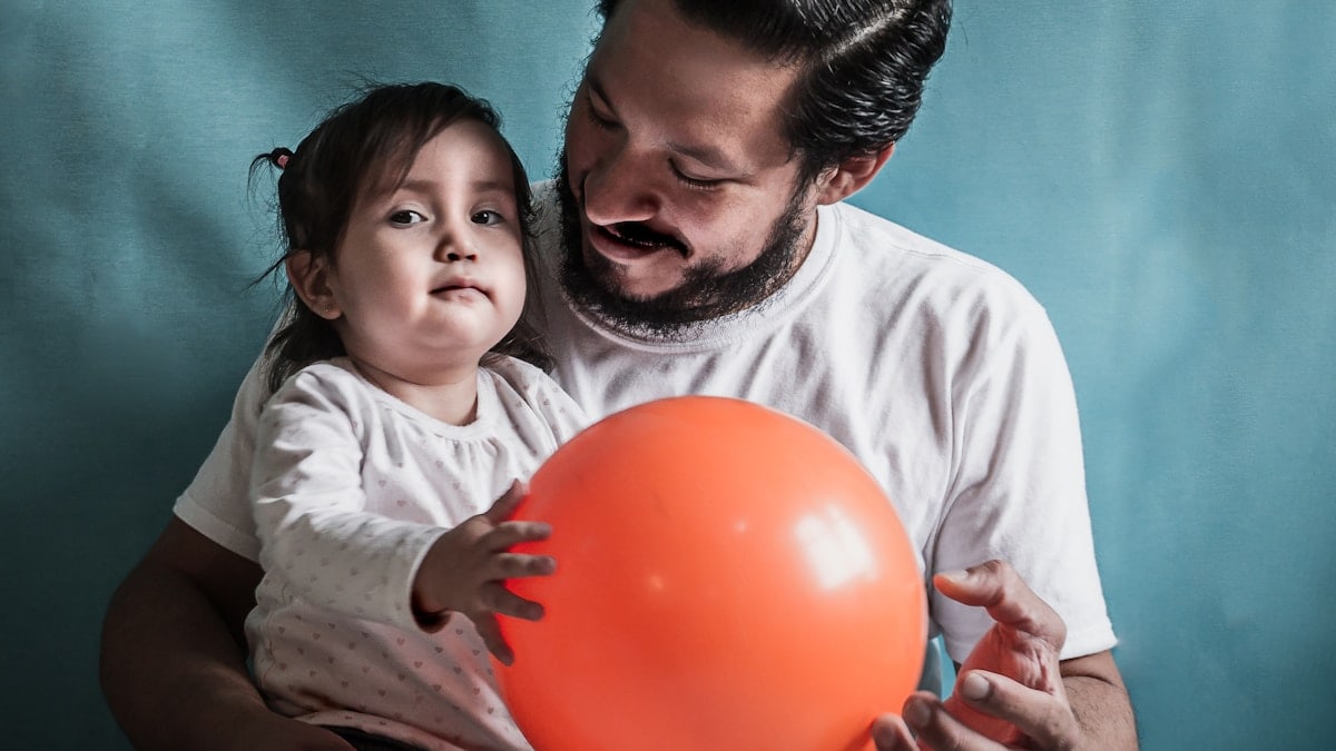 man and baby holding red balloon